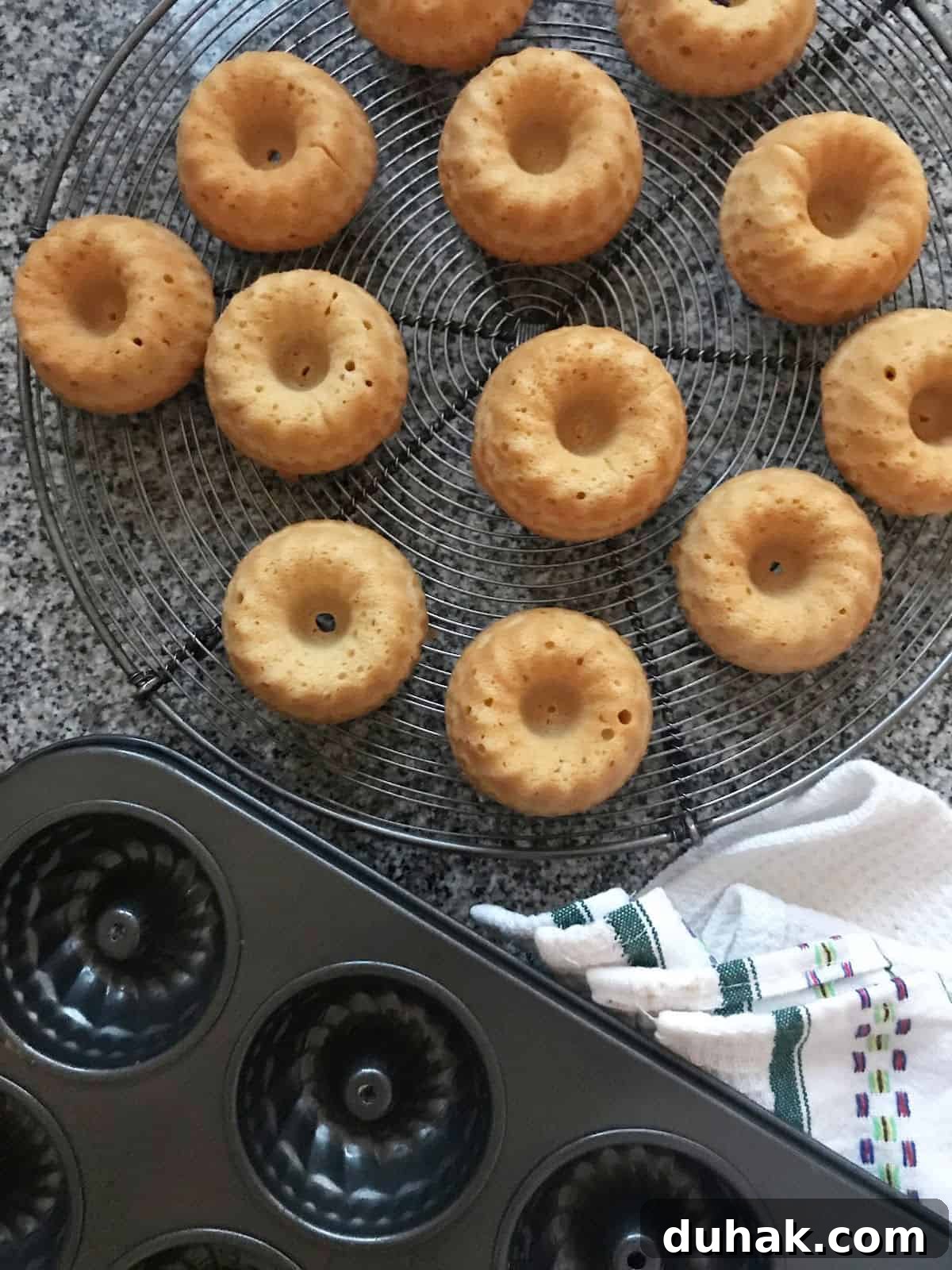 Gray surface, black pan and mini cakes on a wire rack.