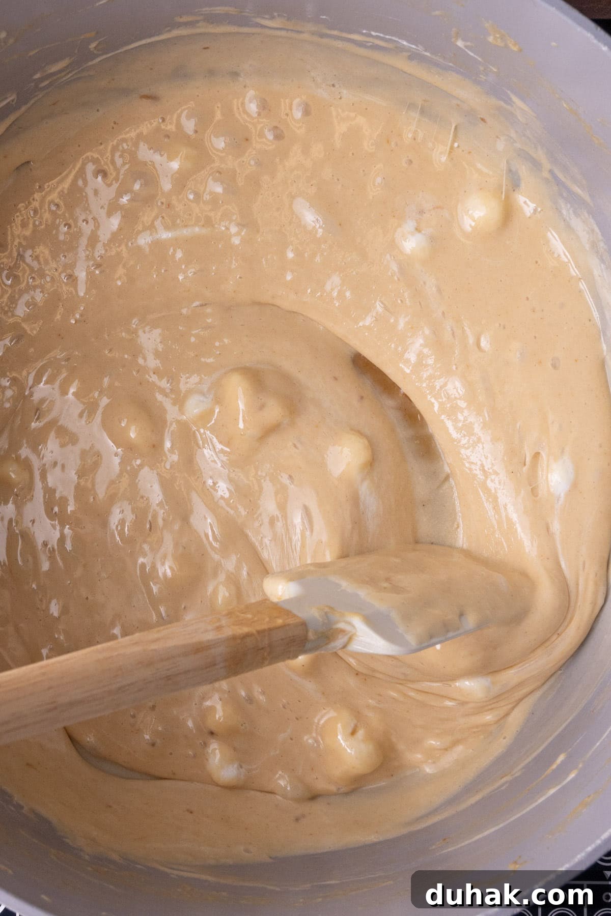 Melted marshmallows mixed with butter and peanut butter in a large pot.