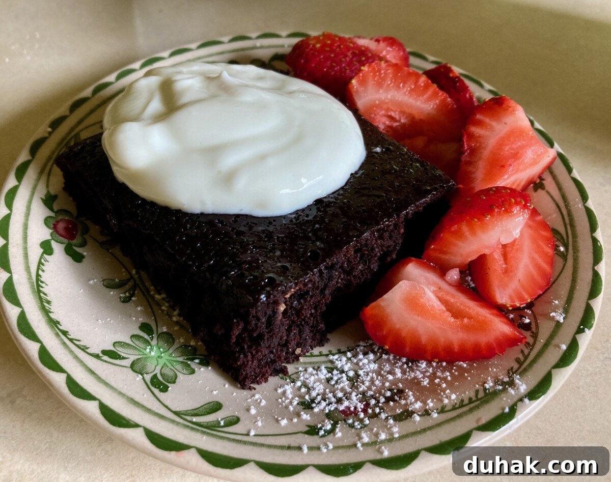 Eggless Wacky Cake Recipe — No Butter, No Milk Needed 7 Piece of Chocolate Depression Cake with dollop of Greek yogurt and fresh strawberry slices.