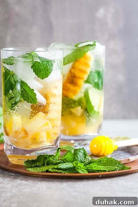 2 glasses of Grilled Pineapple Mojitos with mint and honey