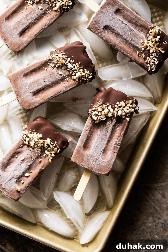Keto chocolate popsicles on a golden baking tray with ice