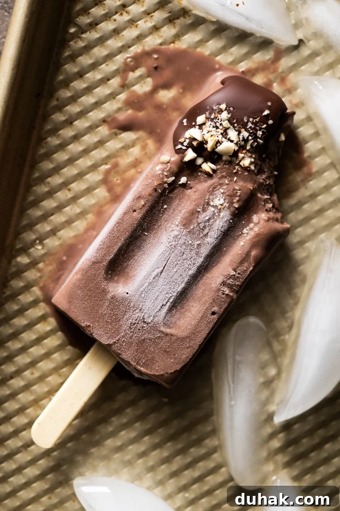 Bitten and melting paleo chocolate popsicle on a golden baking tray