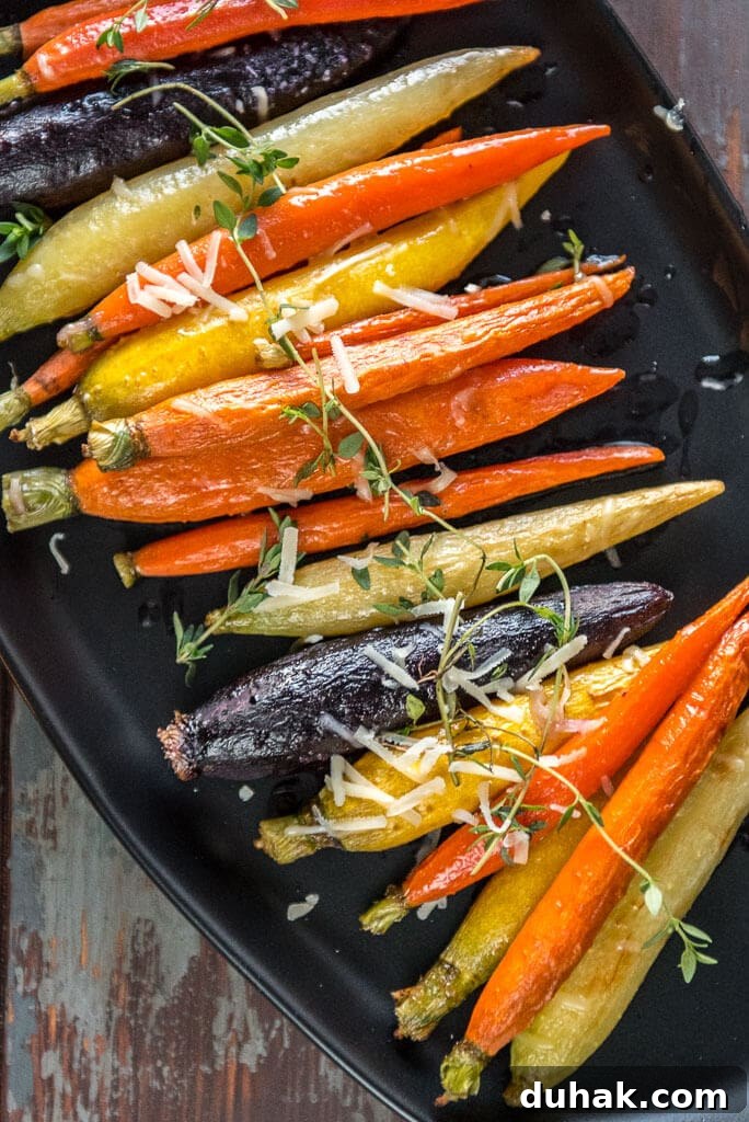 Multi-color oven roasted carrots on black serving platter topped with fresh thyme