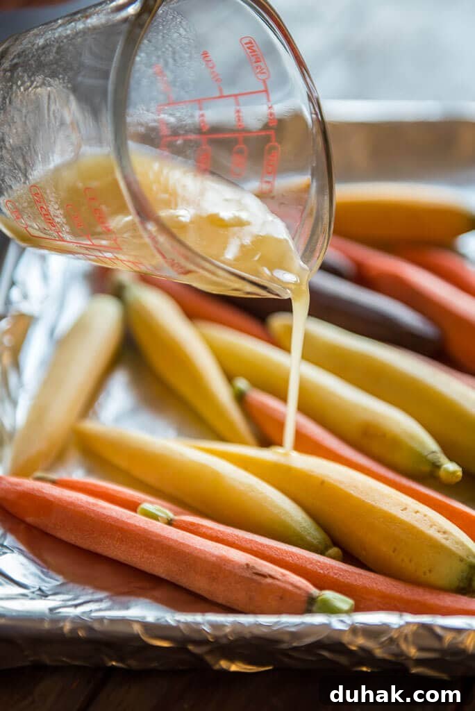 honey butter sauce being drizzled on carrots on baking sheet