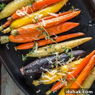 Multi-color oven roasted carrots on black serving platter topped with fresh thyme