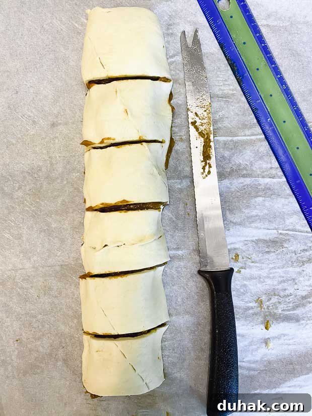 Maple-Banana Pumpkin Cinnamon Rolls with Warm Cinnamon Glaze 8 slicing a rolled cinnamon roll filled with pumpkin and bananas