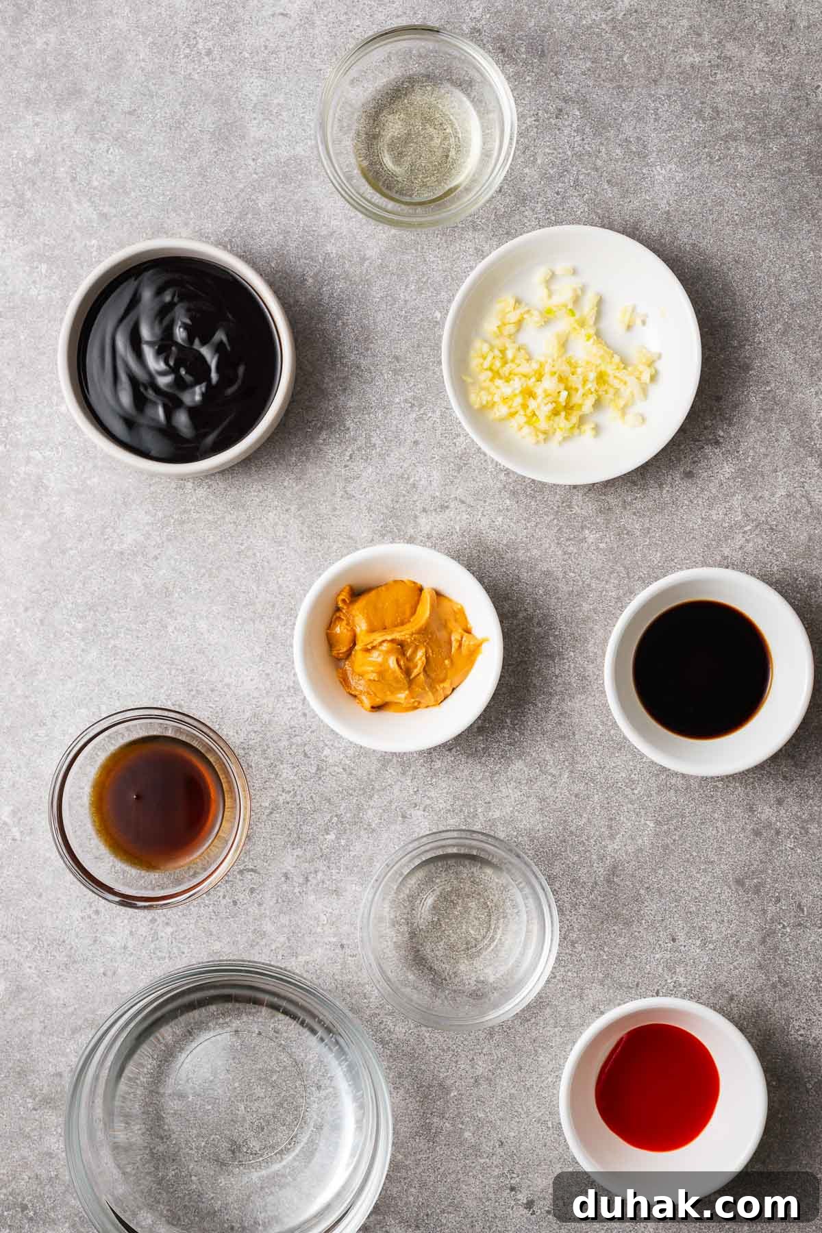 Hoisin Peanut Sauce Recipe for Stir-Fries, Dipping & Marinades 3 Ingredients for hoisin peanut sauce arranged in small bowls including hoisin sauce, peanut butter, minced garlic, toasted sesame oil, sriracha sauce, rice vinegar and water.