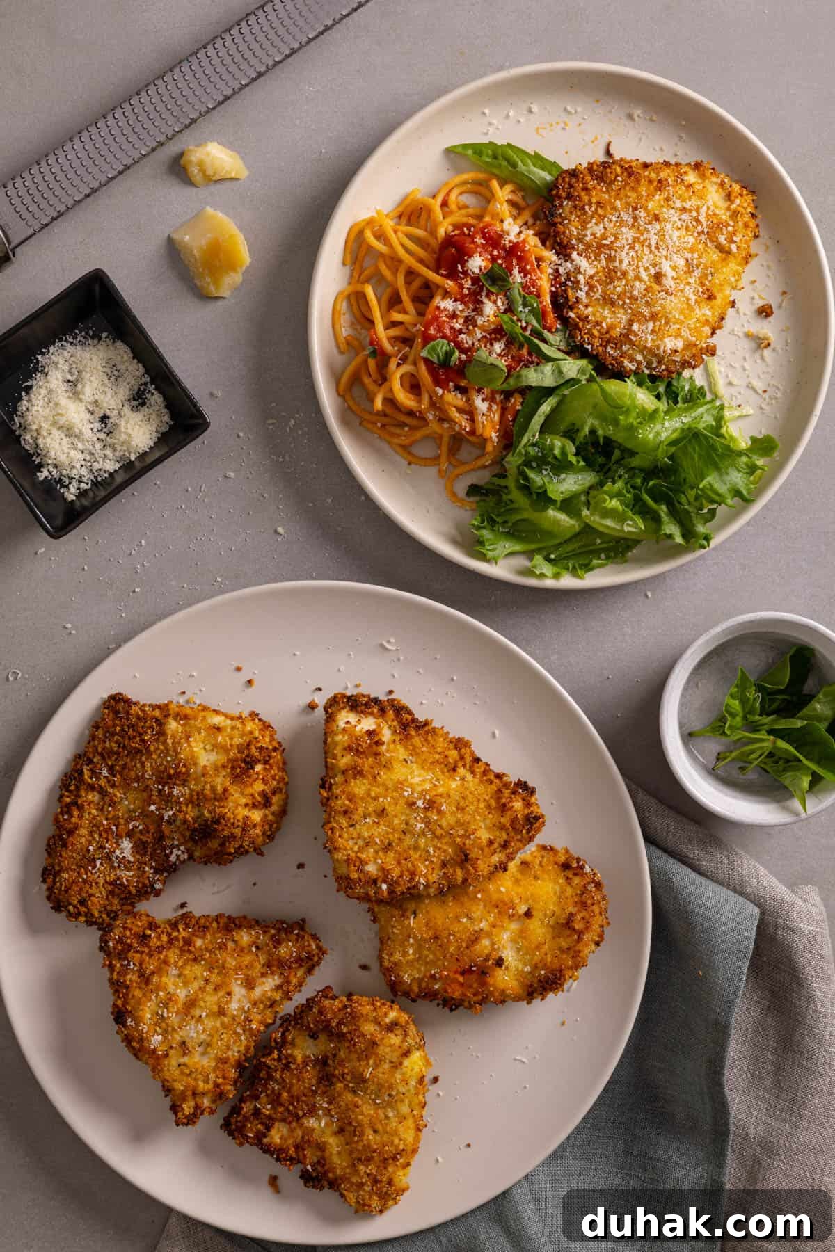 A platter of crispy air fryer parmesan chicken with a serving to the side.