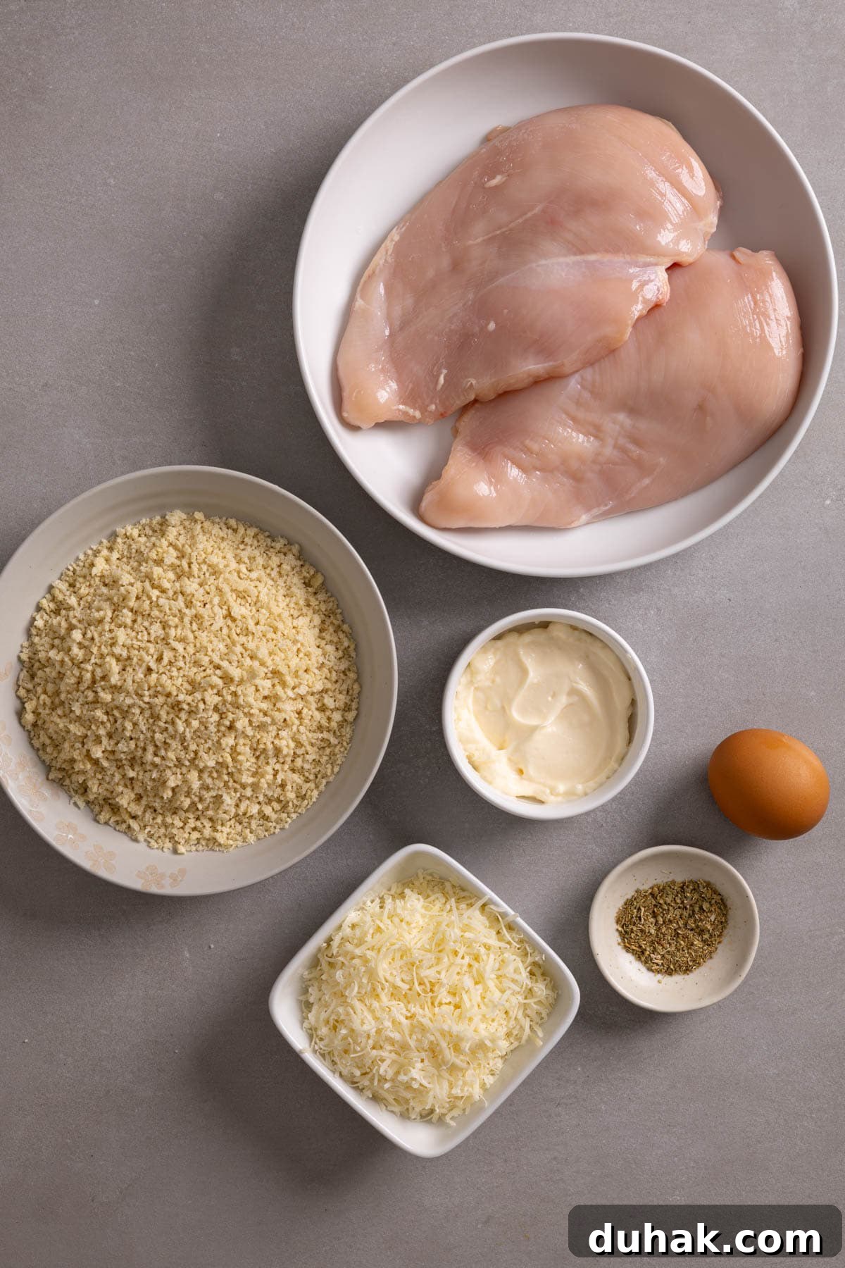 Ingredients for parmesan crusted air fryer chicken on a gray table.