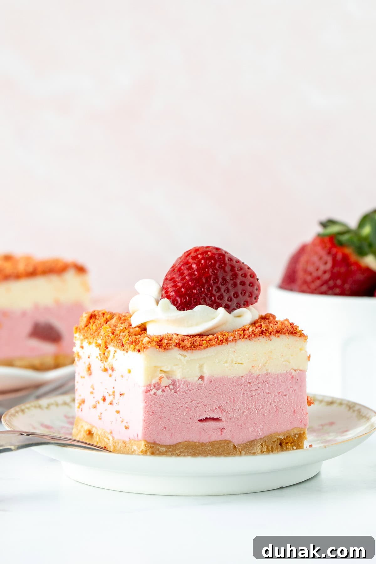 Slice of strawberry shortcake ice cream cake with whipped cream and a strawberry on top