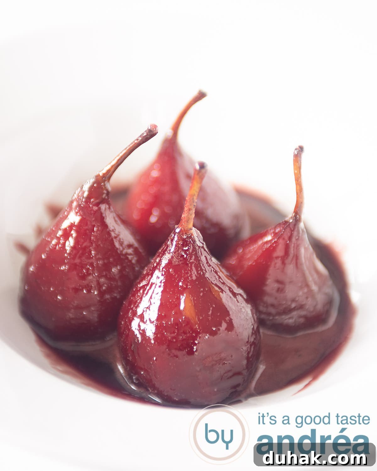 French Port-Poached Pears Recipe — Classic Dessert in Minutes 2 Four poached pears with poaching syrup in a white deep plate