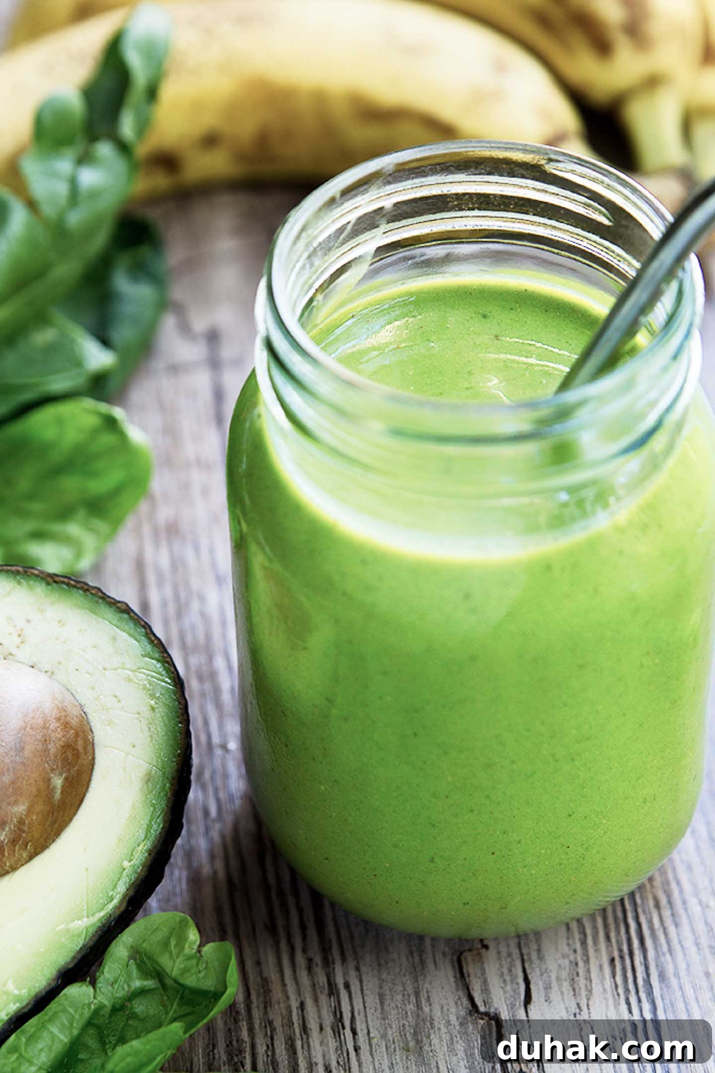 Refreshing Nutrient-Packed Green Smoothie Recipe for Energy 2 Green Smoothie in a mason jar with a straw.