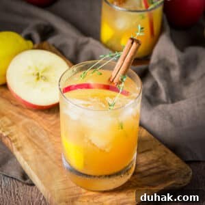 Square photo of a wood board with an apple cider drink in a glass