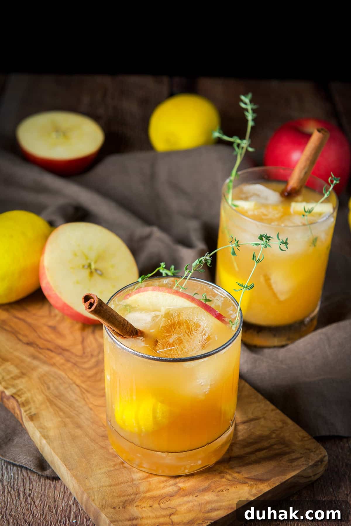 Apple Cider Bourbon Smash Cocktail Recipe 8 A table with fruit on it with two glasses of the apple cider cocktail