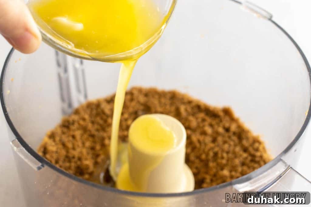 hand pouring melted butter into food processor