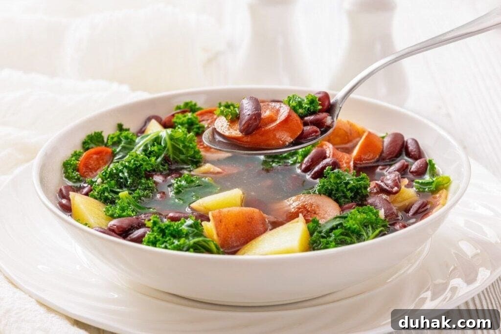 37 Comfort Food Recipes That Keep Reappearing on Menus 16 A bowl of Sausage & Kale Soup with a spoon lifting a portion from the bowl.
