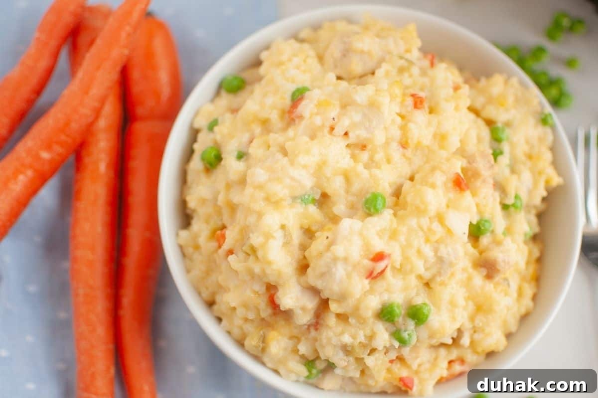 37 Comfort Food Recipes That Keep Reappearing on Menus 18 A bowl of Slow Cooker Chicken and Rice is next to whole carrots on a light blue cloth.