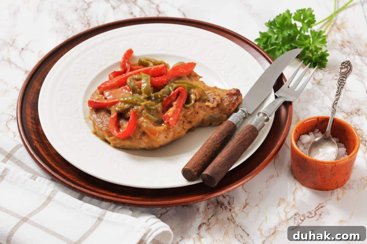 37 Comfort Food Recipes That Keep Reappearing on Menus 38 Smothered Pork Chops on a white plate, served with a fork and knife, next to a small bowl of salt and a sprig of parsley.