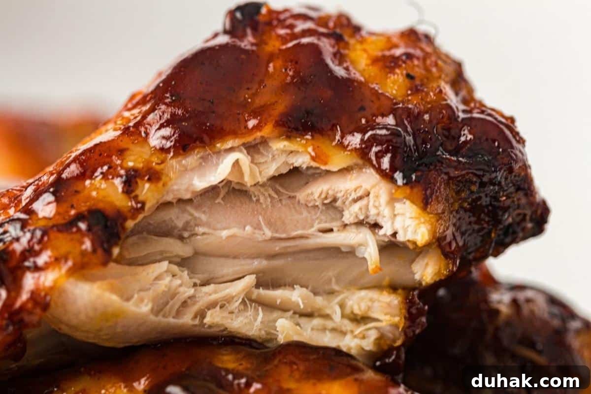 37 Comfort Food Recipes That Keep Reappearing on Menus 6 Close-up of a cooked chicken wing with a bite taken, showing juicy and tender meat covered in dark barbecue sauce.