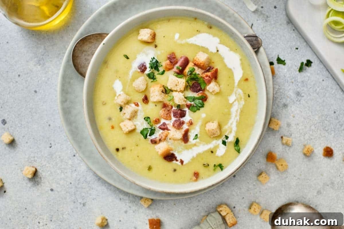 37 Comfort Food Recipes That Keep Reappearing on Menus 9 A bowl of Gordon Ramsay's Leek & Potato Soup is placed on a plate with a spoon nearby.