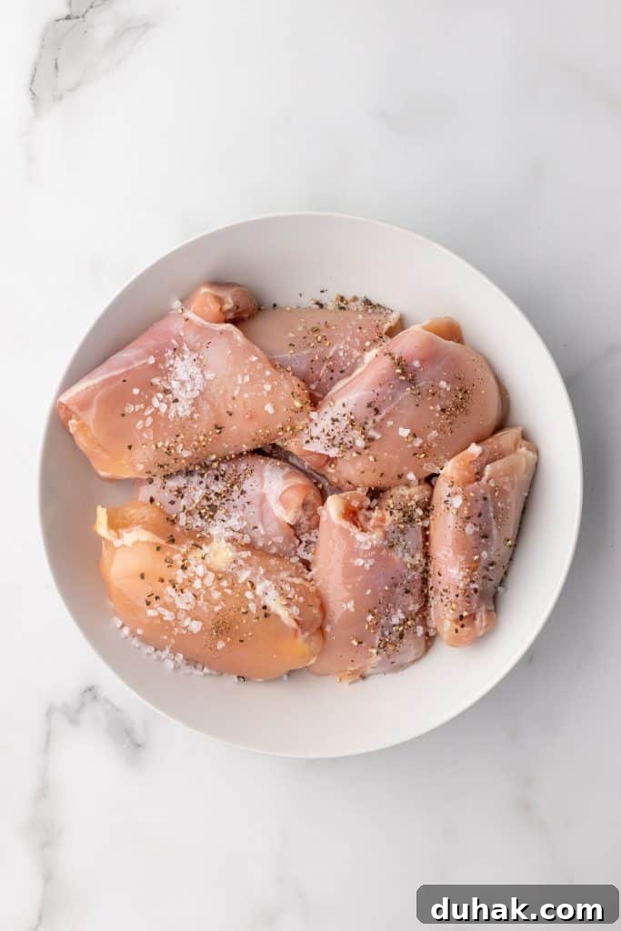 Pan-Seared Chicken Thighs with Creamy Garlic Gravy 5 salt and pepper seasoned raw chicken thighs in a shallow white bowl