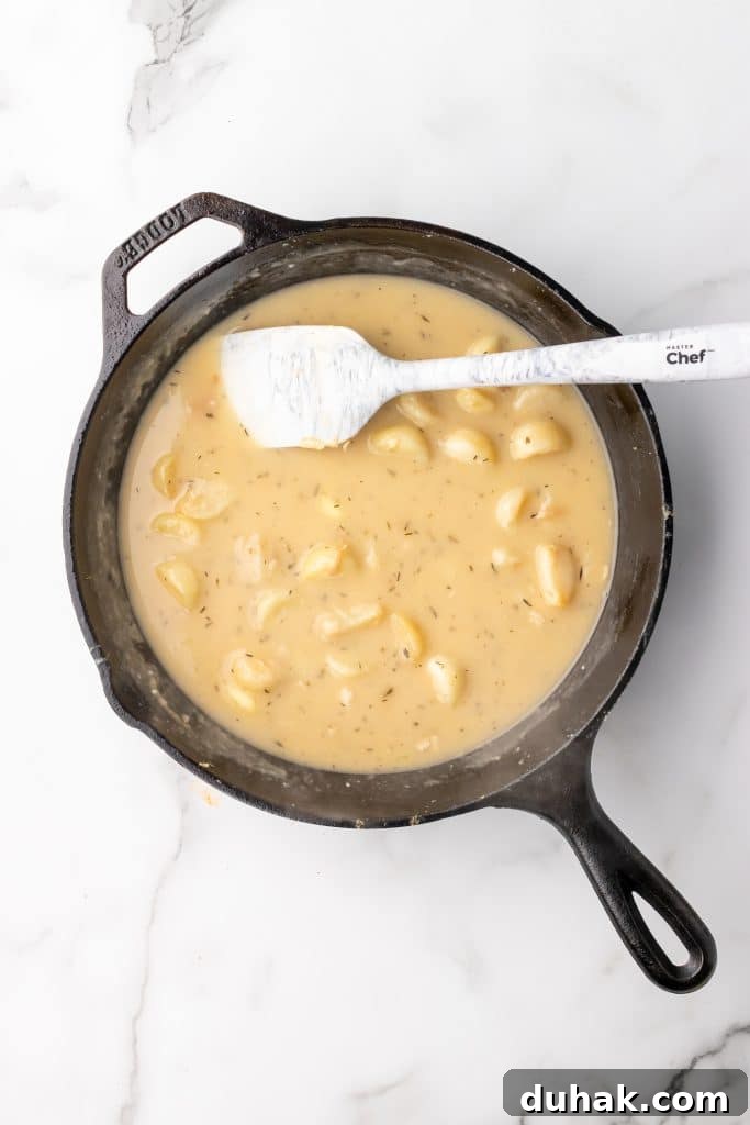Pan-Seared Chicken Thighs with Creamy Garlic Gravy 6 herbs and whole cloves in a brown garlic gravy in a black cast iron skillet