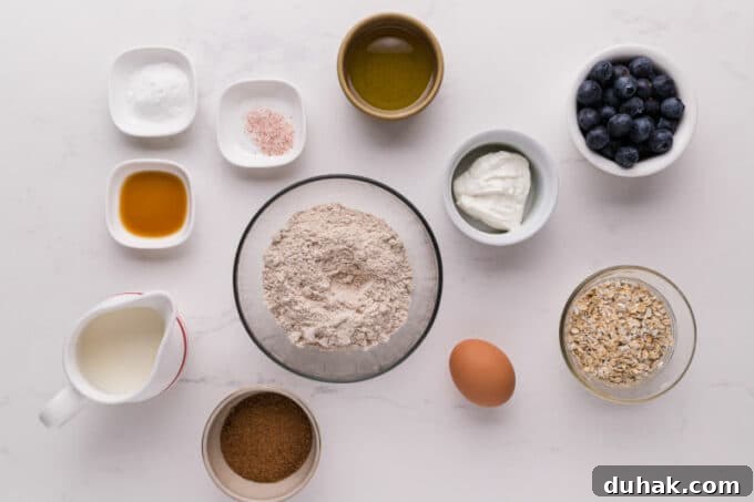 Flour, oats, blueberries, and other ingredients for muffins laid out on a table.
