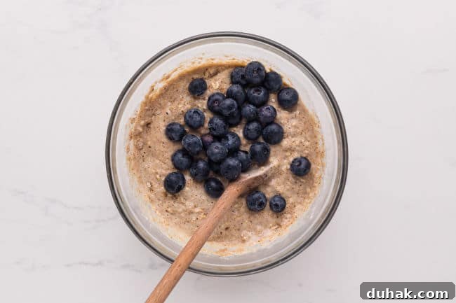 Stirring muffin batter with fresh blueberries.