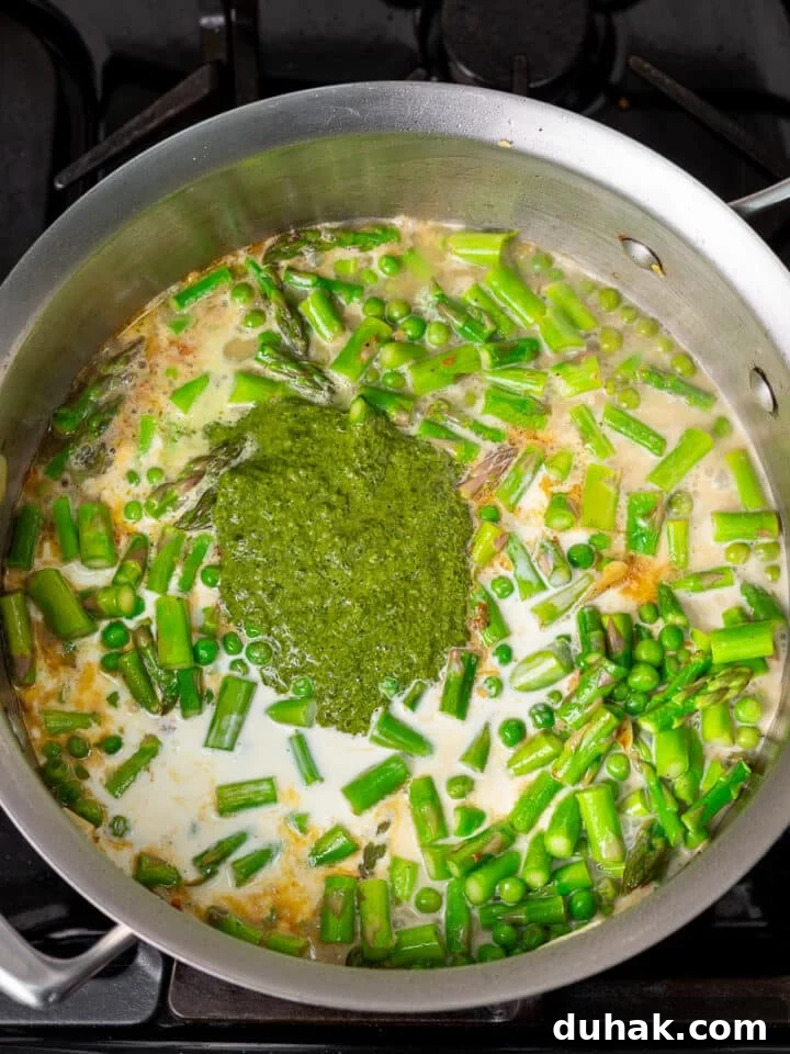 Creamy Salmon Pesto Pasta with Lemon Zest 11 pesto, cream, white wine and parmesan cheese added to veggies in pan