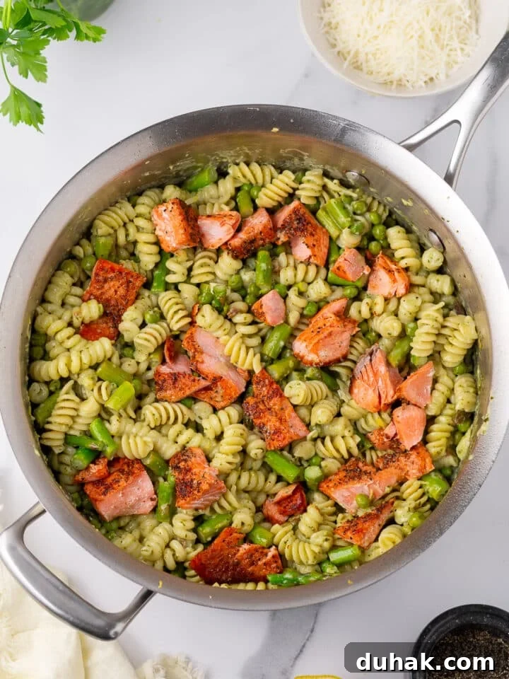 Creamy Salmon Pesto Pasta with Lemon Zest 16 salmon pesto pasta in stainless steel skillet, bowl of parmesan cheese, parsley