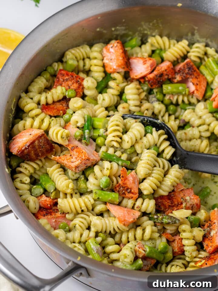 Creamy Salmon Pesto Pasta with Lemon Zest 4 big black spoon in a skillet of salmon pesto pasta