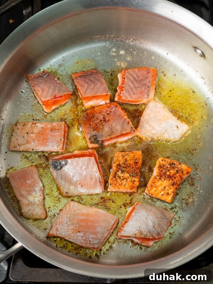 Creamy Salmon Pesto Pasta with Lemon Zest 8 pieces of salmon being seared in a stainless steel skillet
