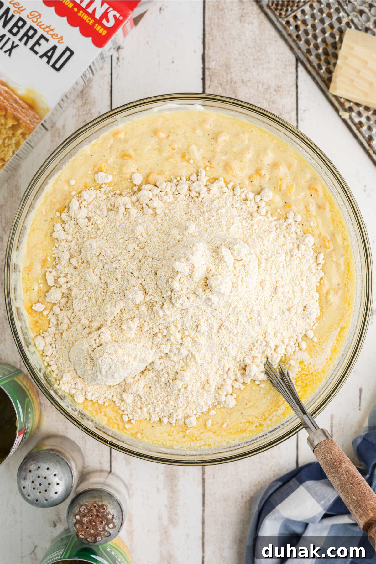 Cornbread mix added to a mixing bowl with other ingredients.