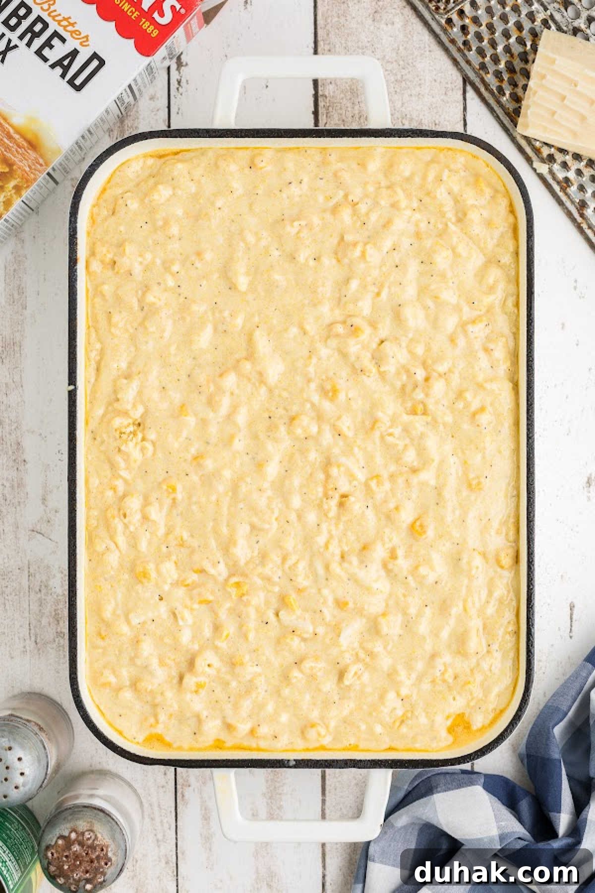 Cornbread pudding poured into a casserole dish, about to be baked.