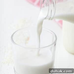 square image of a glass of milk being poured into a cup from jar