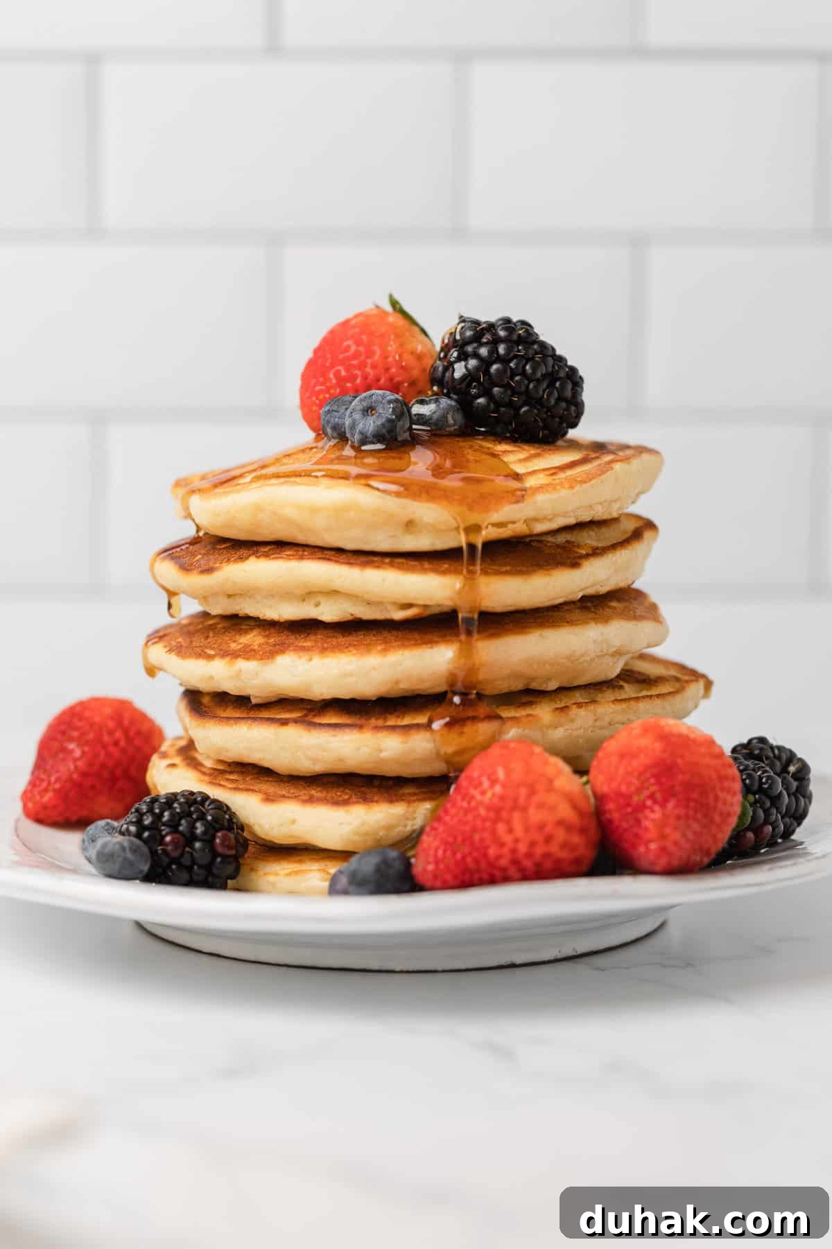 a stack of pancakes with fresh fruit and syrup