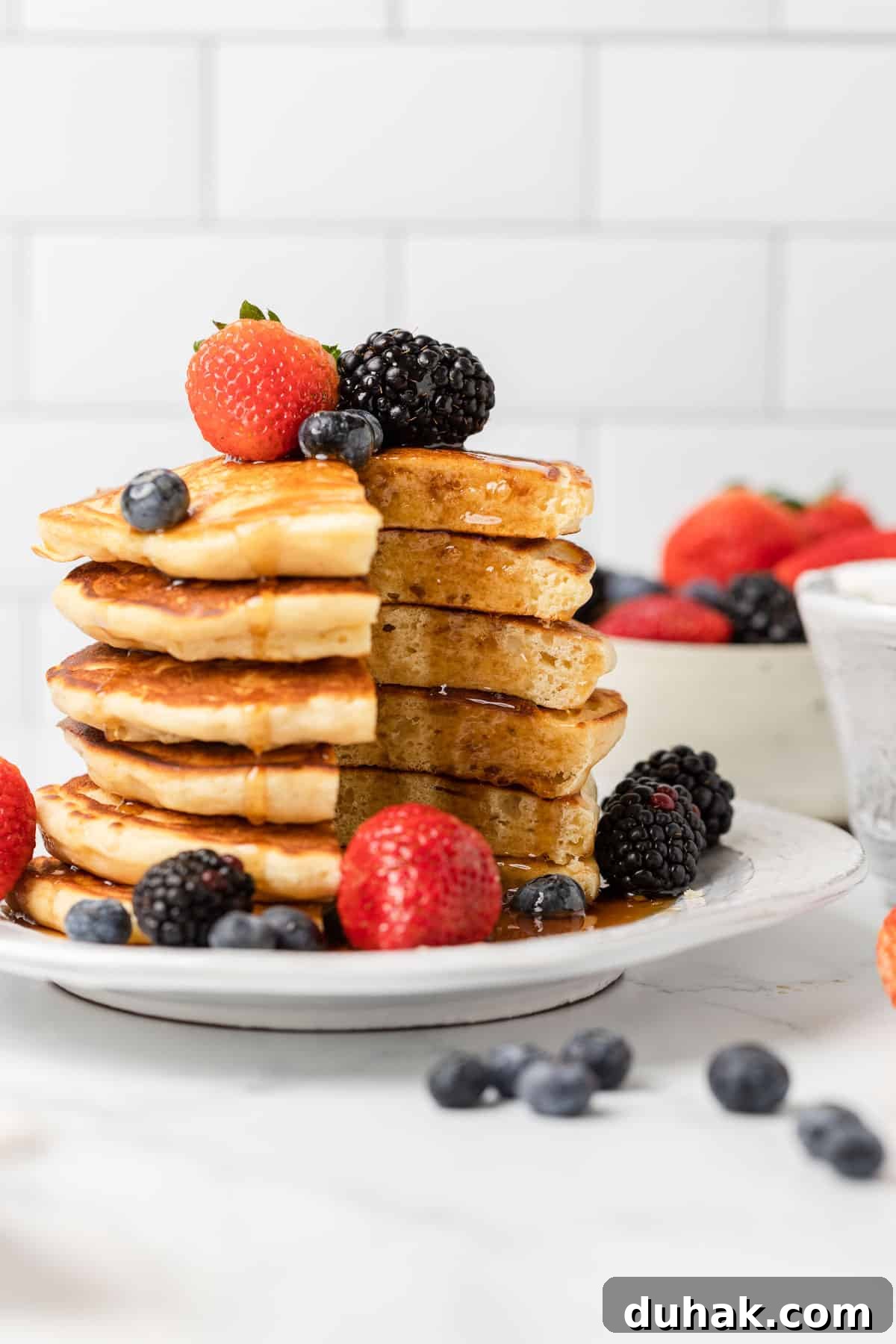 a stack of pancakes cut through with fruit and syrup