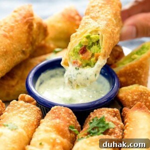 An avocado egg roll dipped in sauce.