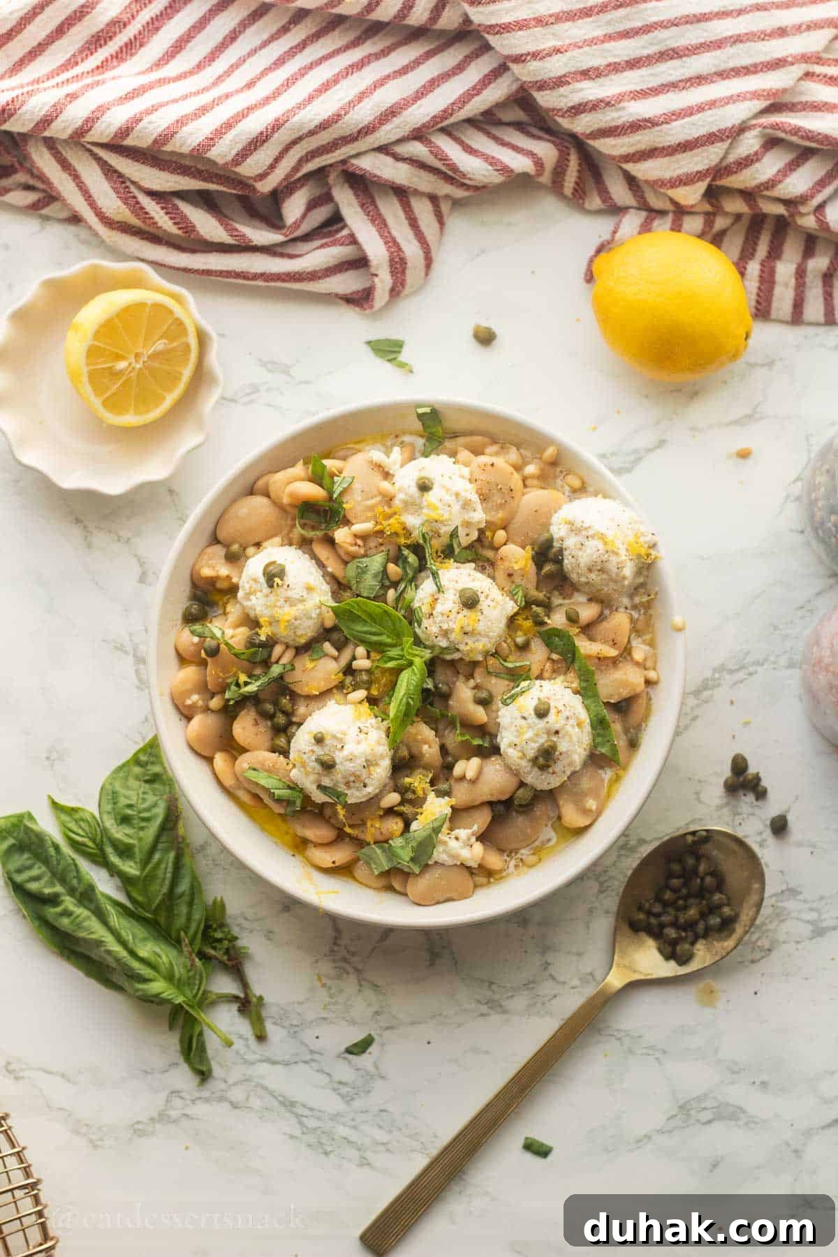 Creamy Ricotta and Butter Bean Salad with Lemon Herb Dressing 9 Butter bean salad with ricotta in bowl with lemons and spoon of capers beside it.