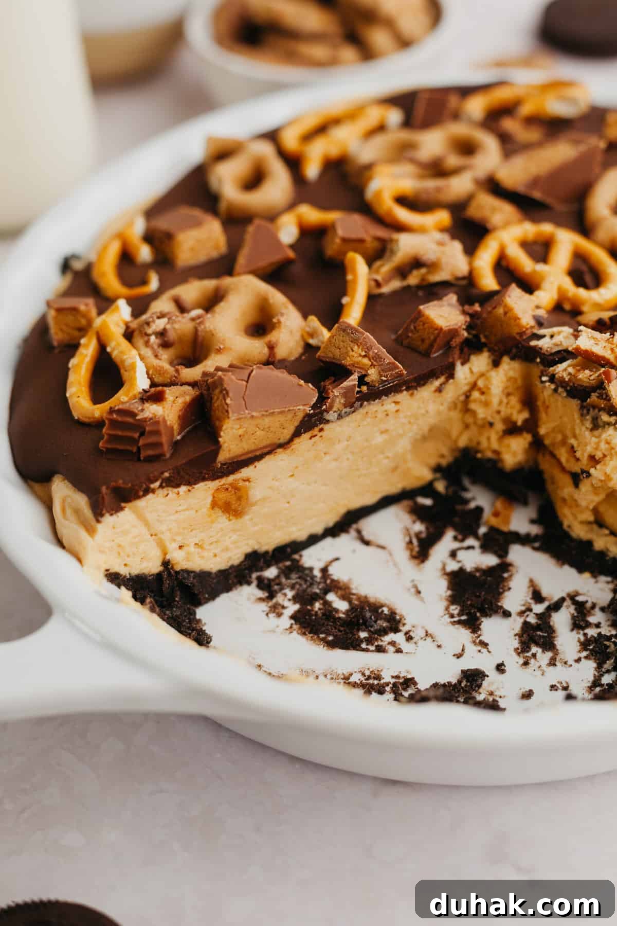 An oreo peanut butter pie in a white dish, some slices have been cut.