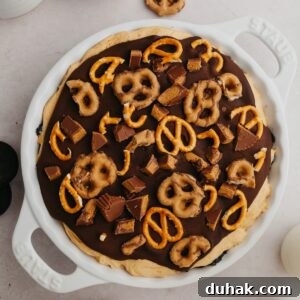 An overhead shot of a pie dish with a peanut butter pie covered in ganache and pretzels.