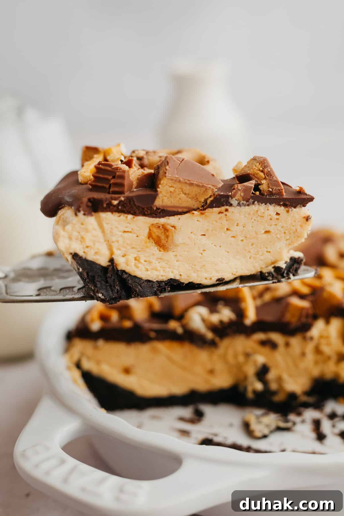 A silver cake server lifting up an Oreo peanut butter pie slice.
