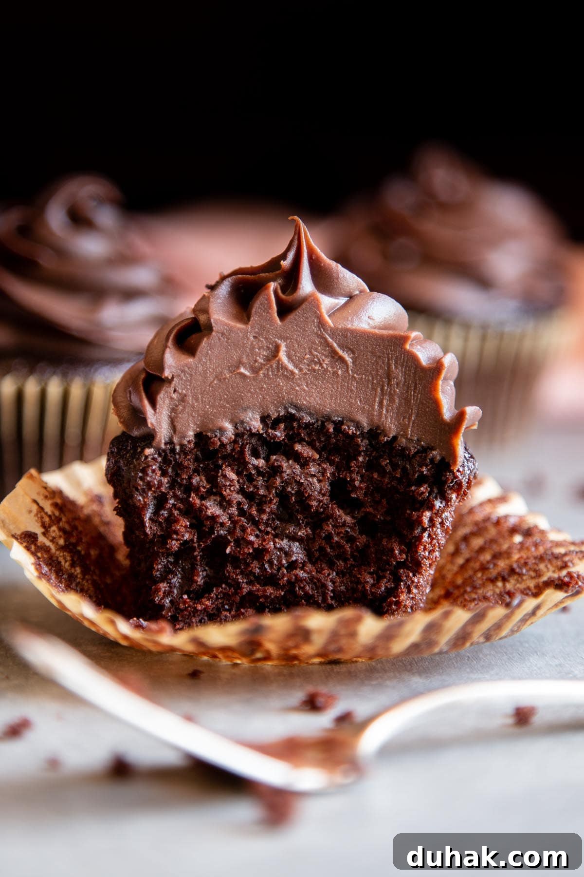 Chocolate ganache frosting on a chocolate cupcake split in half.
