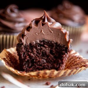 Chocolate ganache frosting on a chocolate cupcake split in half.