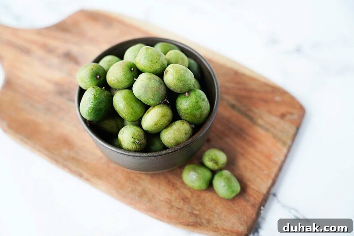 Kiwi Berries: Small Fruit Guide, Taste, Uses, and Benefits 3 Kiwi Berries in a bowl on top of a cutting board
