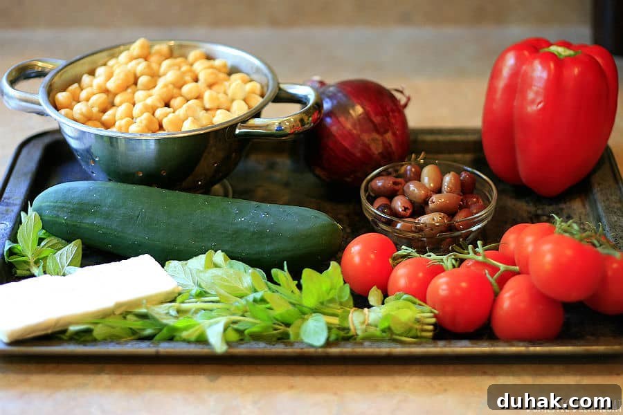 Greek Chickpea & Quinoa Salad with Feta and Lemon Dressing 2 The ingredients to make chickpea and quinoa salad on a baking sheet: chickpeas, red onion, red pepper, cucumber, kalamata olives, tomatoes, oregano, Feta