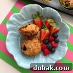 Two muffins in a baby blue,flower shaped bowl, served with fresh berries.