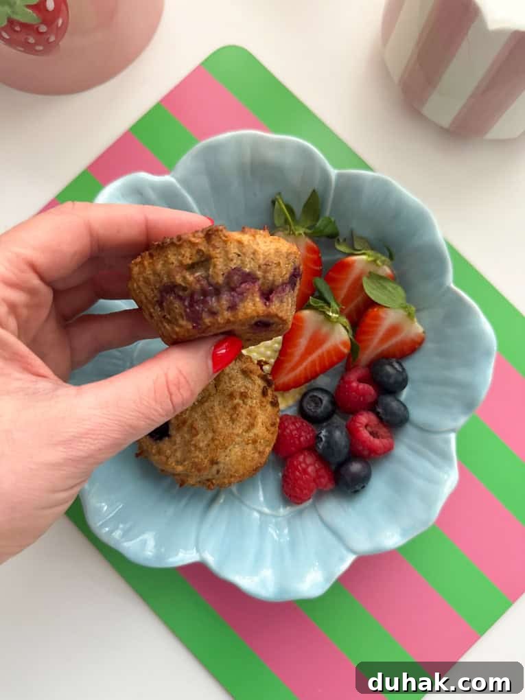 Two muffins in a baby blue,flower shaped bowl, served with fresh berries.