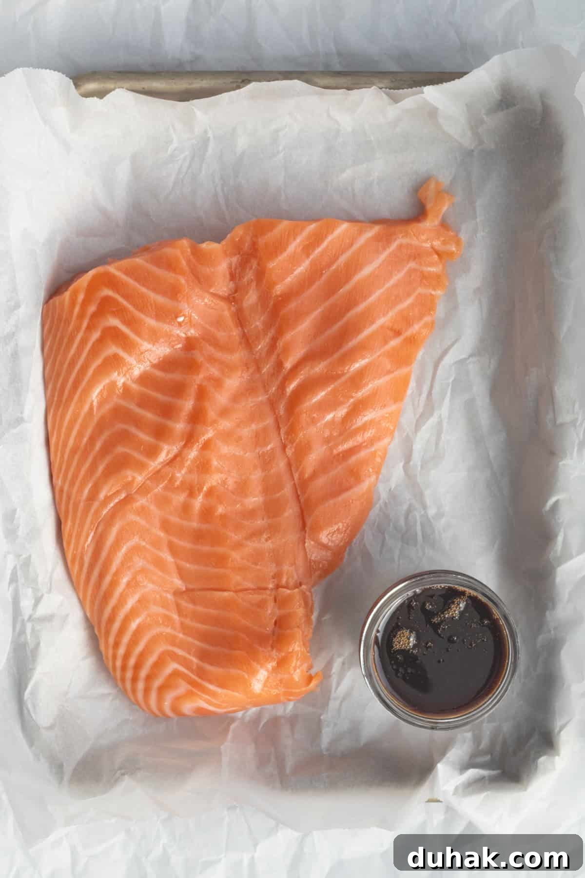 salmon and soy sauce on a parchment lined sheet pan.