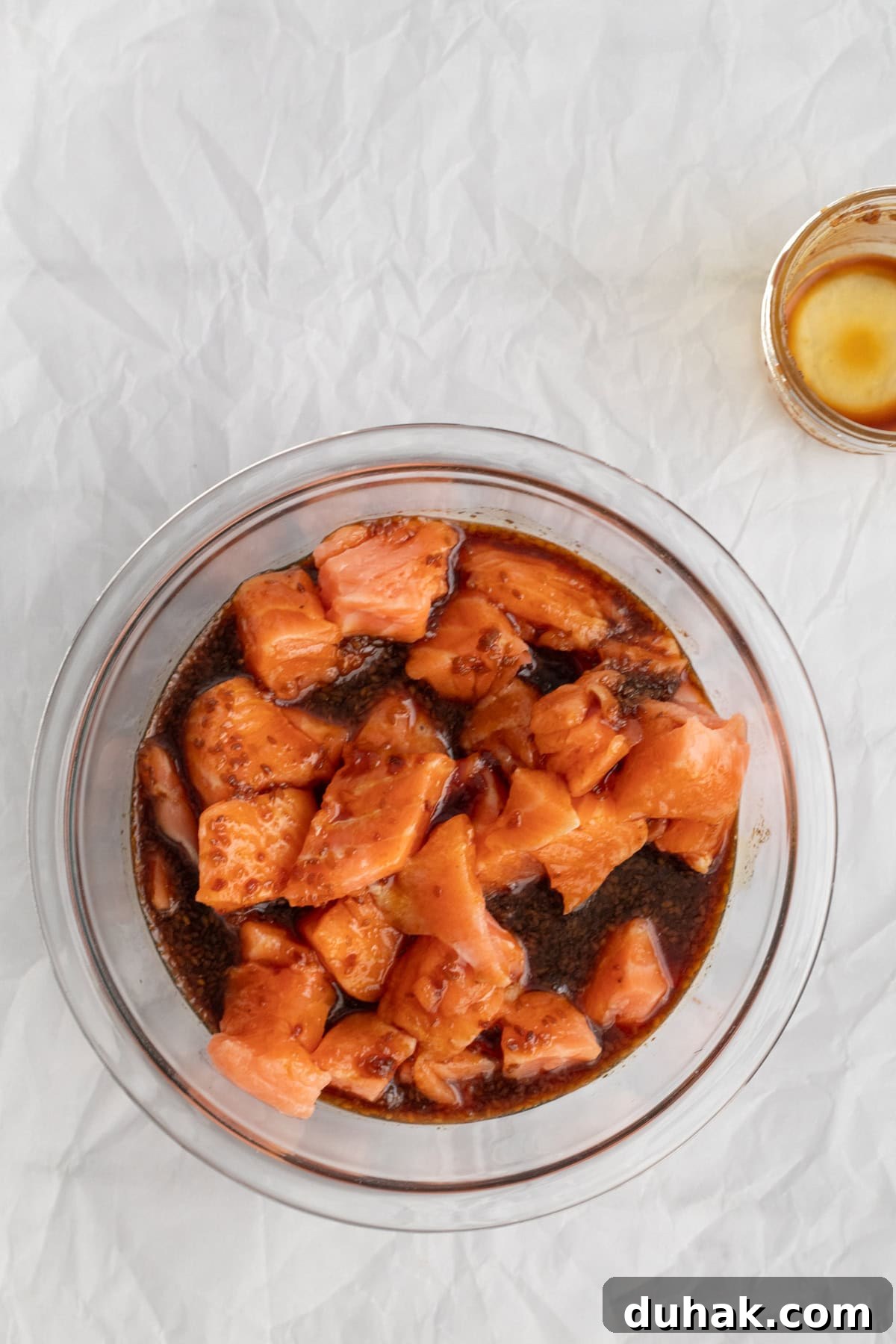 salmon marinating in a glass bowl.